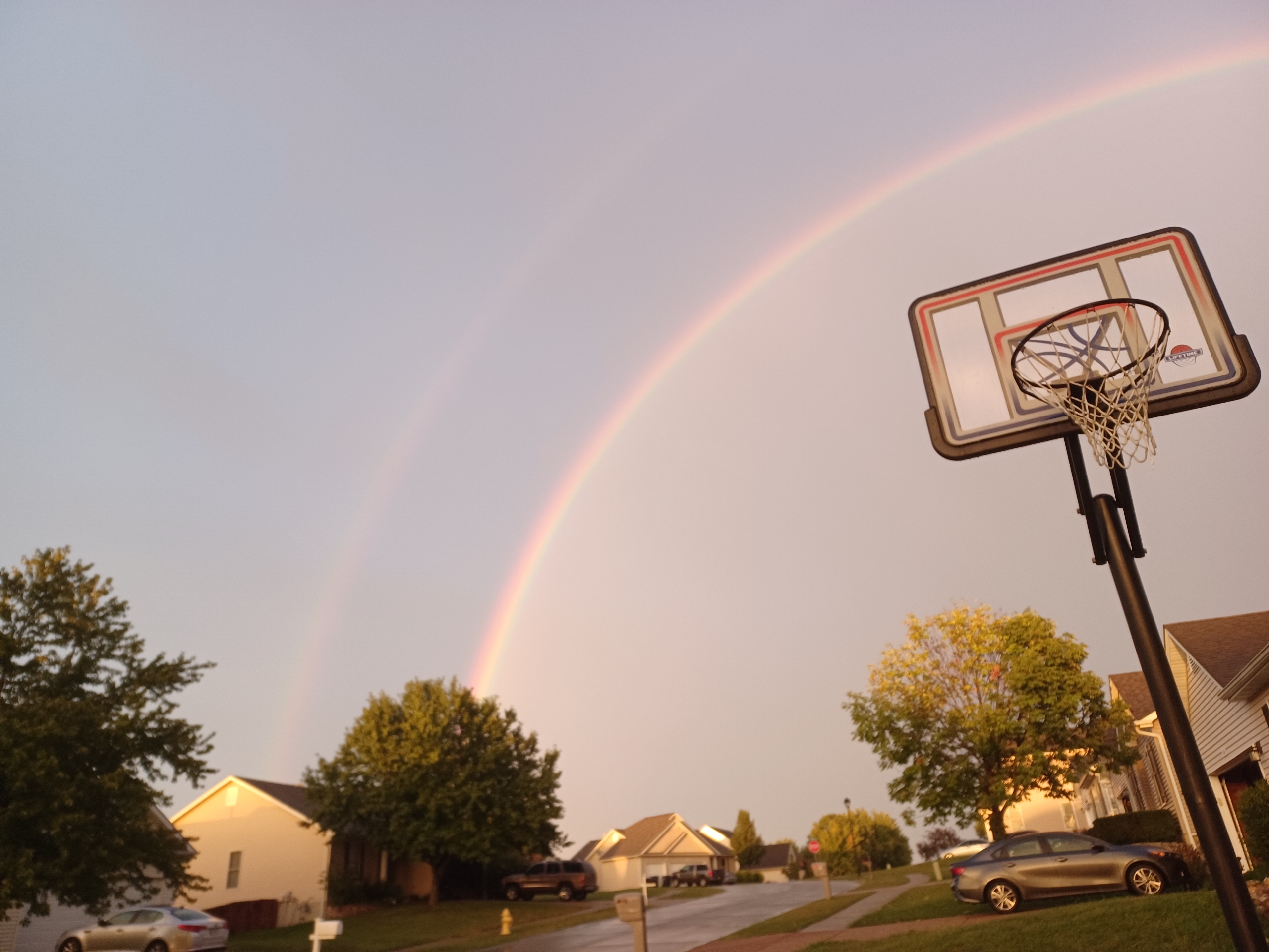 Photo of a basketball hoop with a rainbow over the top