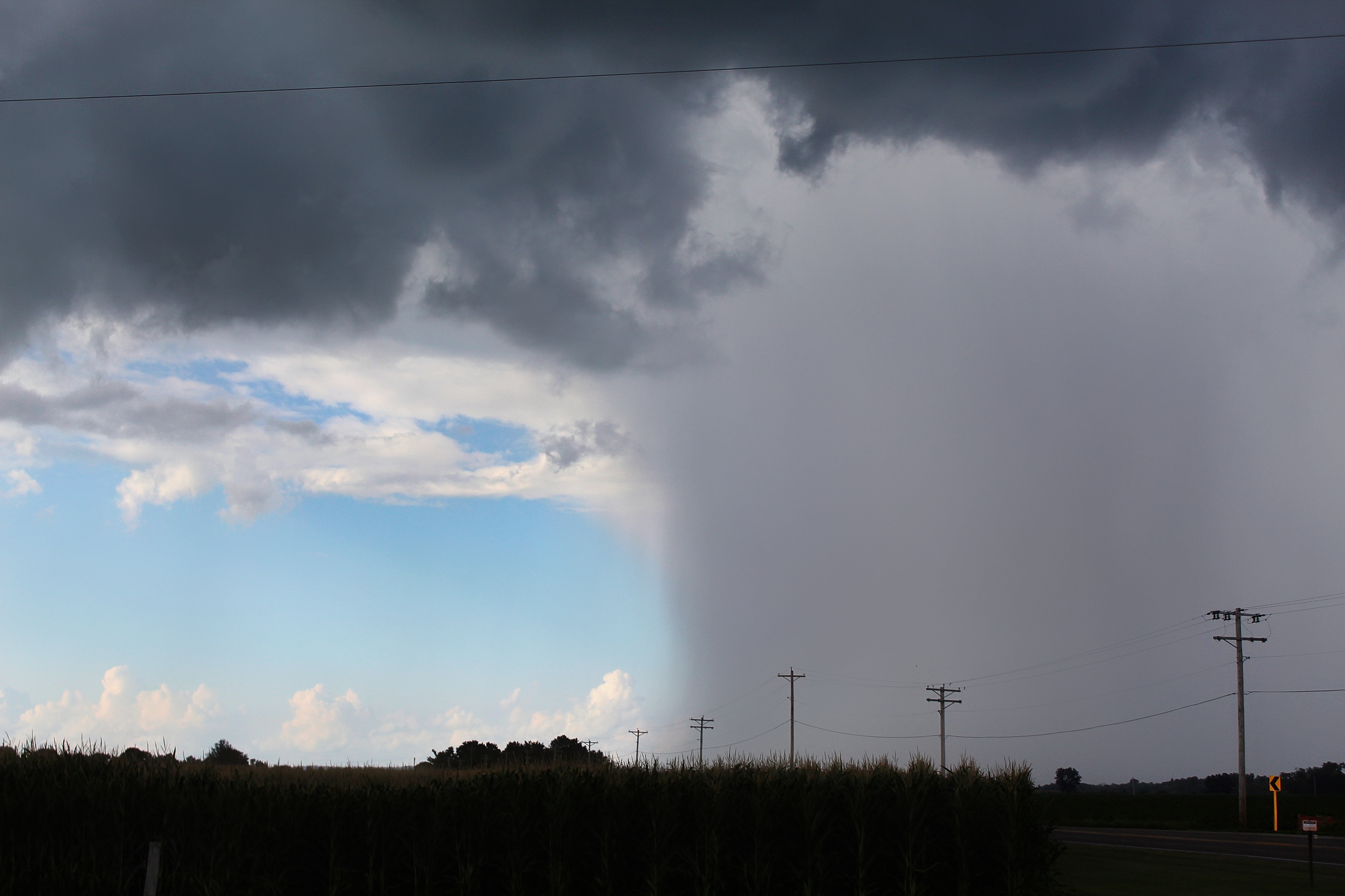 The sky during and after a storm caught in one picture. Right side is completely grey while the left has bright blue skies peeking from below dark clouds.