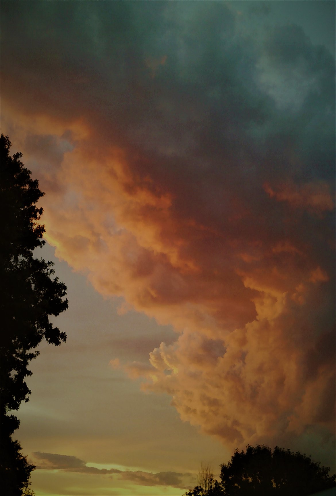 Ominous billowing clouds with a gradient of orange to pink to green