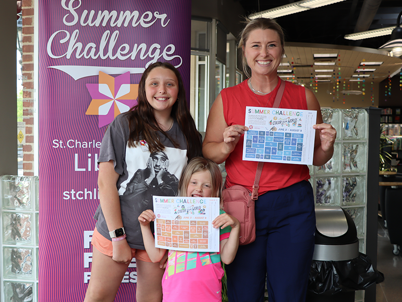 a family showing off their summer challenge game boards