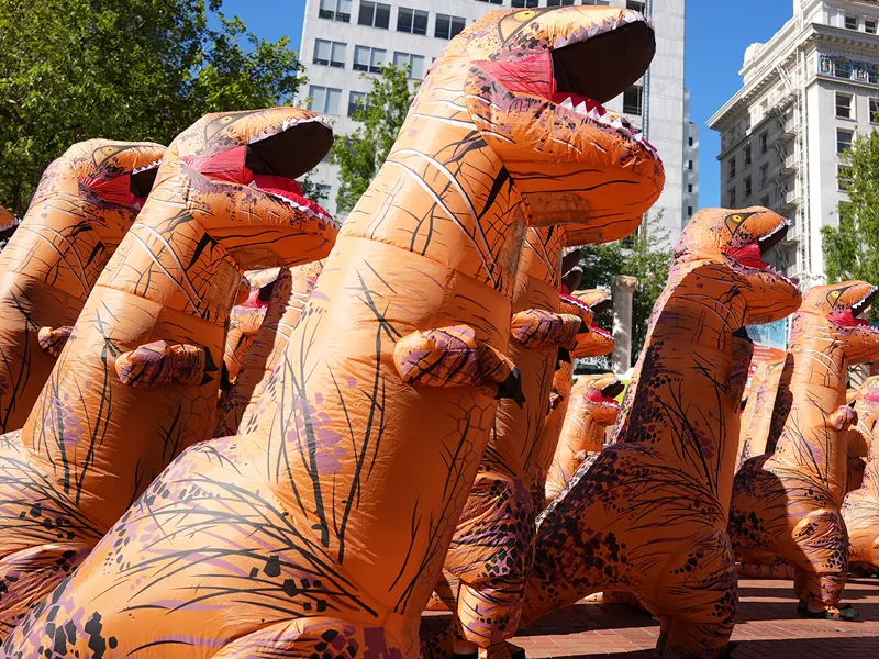 a group of people in inflated dinosaurs