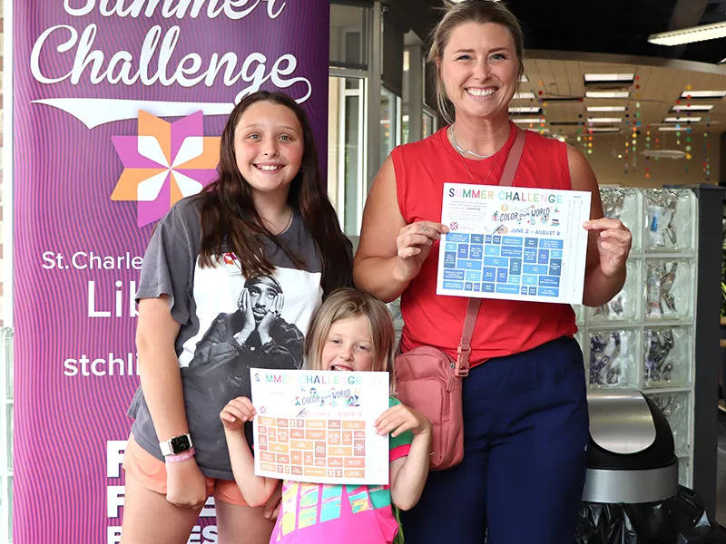 a family holding up their paper gameboards for summer challenge
