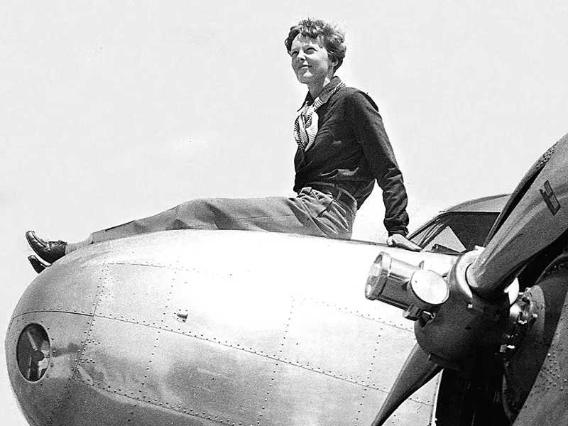 Amelia Earhart sitting on top of her plane