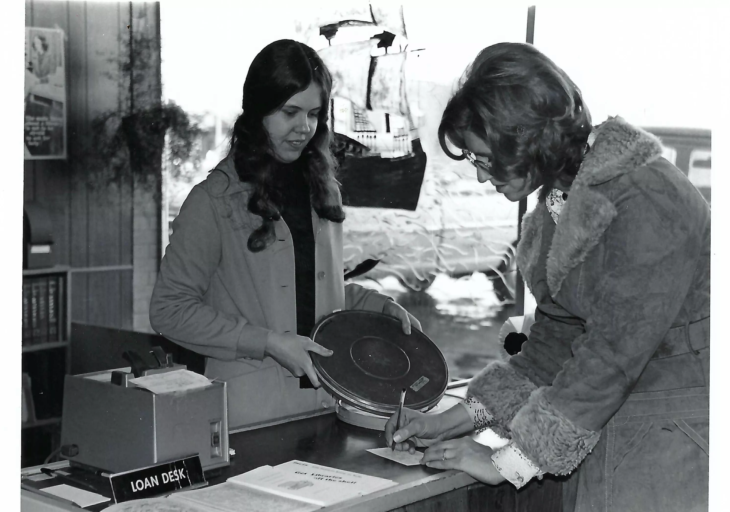black and white image of woman checking out a film reel